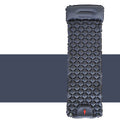 Black inflatable camping mattress with pillow and quilted surface on white and dark background
